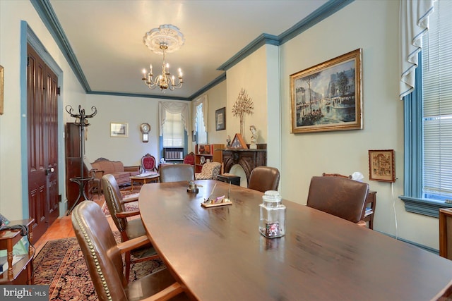 dining area with hardwood / wood-style flooring, ornamental molding, and a chandelier