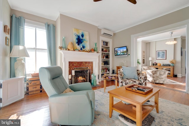 living room featuring a wall mounted AC, a brick fireplace, light wood-type flooring, ornamental molding, and ceiling fan