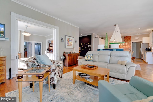 living room with light hardwood / wood-style flooring, crown molding, and a notable chandelier