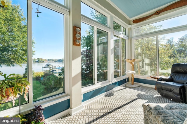 sunroom with ceiling fan and a water view