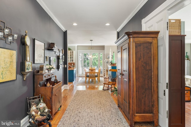 hallway with crown molding and light hardwood / wood-style flooring