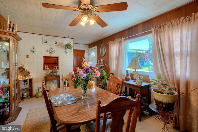 dining room with ceiling fan and wooden walls