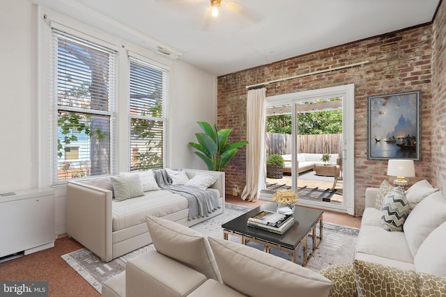 carpeted living room featuring ceiling fan, a wealth of natural light, and brick wall