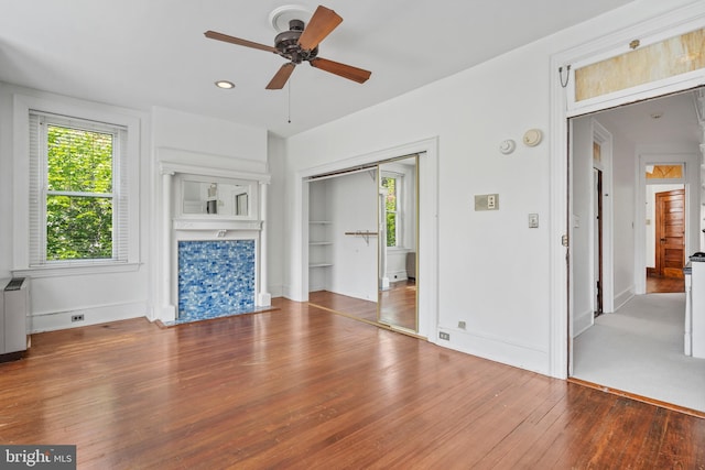 unfurnished living room featuring ceiling fan and hardwood / wood-style flooring