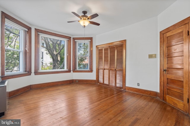 unfurnished bedroom with multiple windows, ceiling fan, hardwood / wood-style floors, and a closet