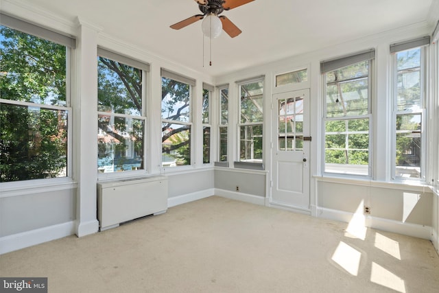 unfurnished sunroom featuring a wealth of natural light, ceiling fan, and radiator heating unit