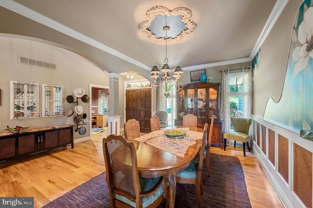 dining room featuring ornamental molding, light hardwood / wood-style floors, and ornate columns