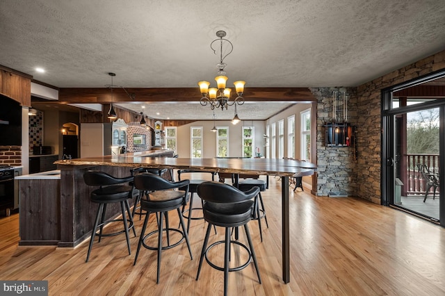 kitchen with decorative light fixtures, kitchen peninsula, a textured ceiling, and beam ceiling