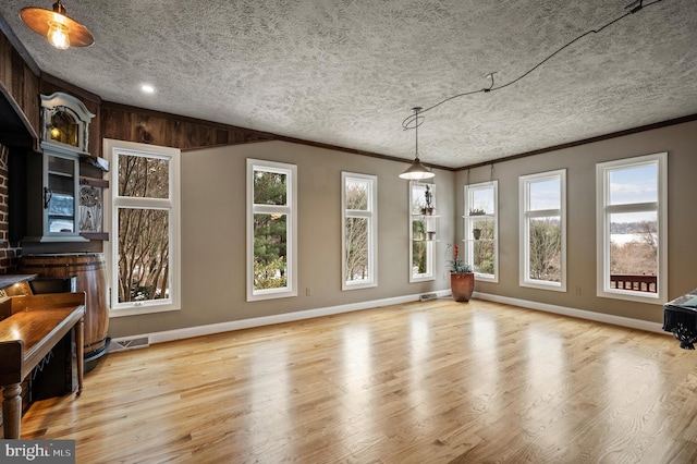 unfurnished living room featuring ornamental molding, a textured ceiling, and light hardwood / wood-style floors