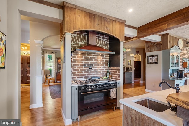 kitchen with beamed ceiling, a textured ceiling, double oven range, sink, and decorative columns