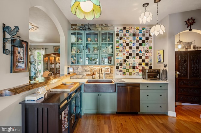 kitchen with sink, light hardwood / wood-style flooring, stainless steel dishwasher, backsplash, and pendant lighting