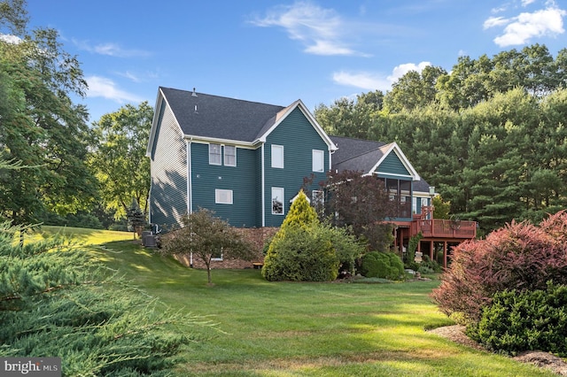 view of side of property with a wooden deck and a lawn