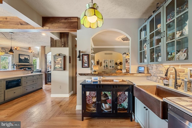 kitchen featuring black microwave, kitchen peninsula, a textured ceiling, stainless steel dishwasher, and sink