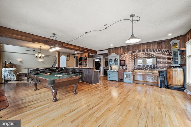 playroom with wood walls, pool table, light wood-type flooring, brick wall, and a textured ceiling