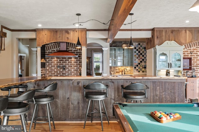 interior space featuring light hardwood / wood-style flooring, billiards, hanging light fixtures, tasteful backsplash, and beam ceiling