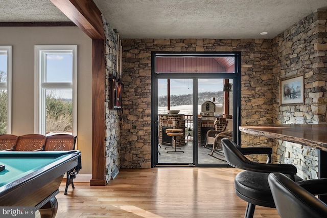 interior space with pool table, a textured ceiling, and light wood-type flooring