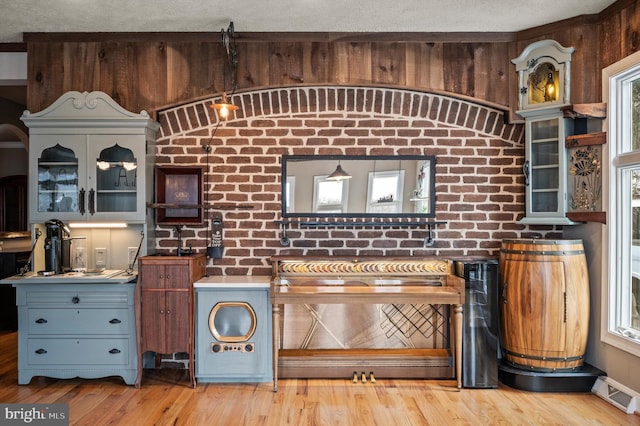 kitchen with light wood-type flooring, plenty of natural light, and brick wall