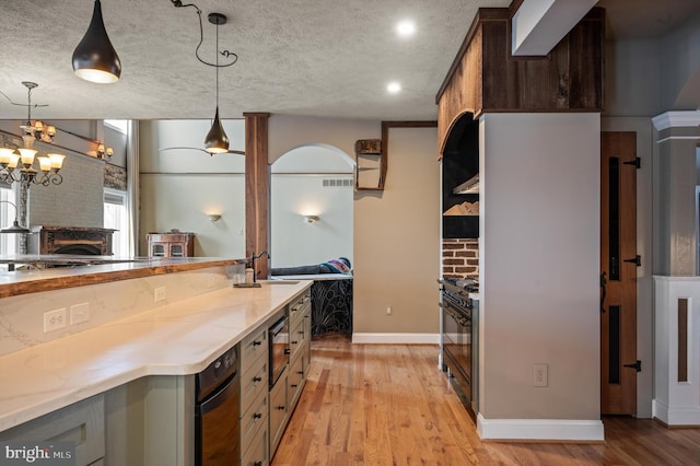 kitchen with sink, decorative light fixtures, a textured ceiling, light hardwood / wood-style floors, and dark brown cabinets