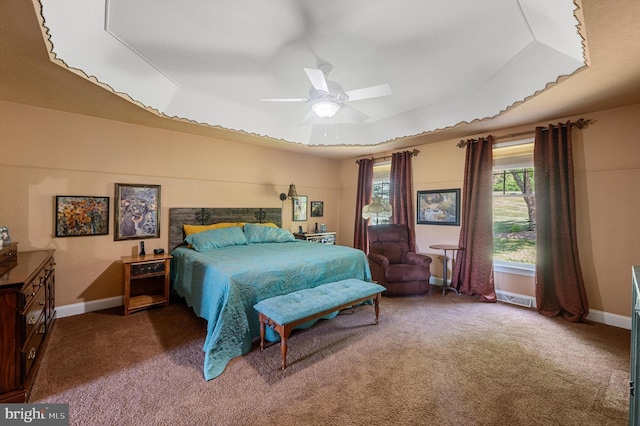 bedroom featuring dark carpet, ceiling fan, and a tray ceiling