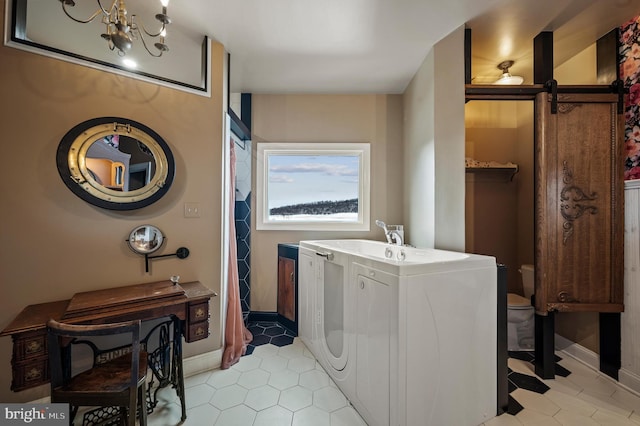 laundry room with washer / clothes dryer, a notable chandelier, and a barn door