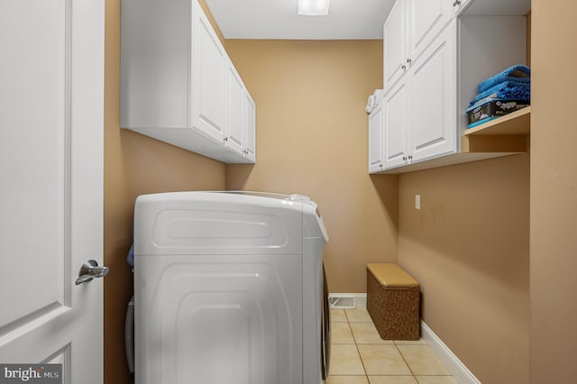 clothes washing area featuring cabinets, washer / dryer, and light tile patterned floors