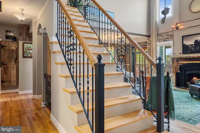 staircase featuring wood-type flooring and a brick fireplace