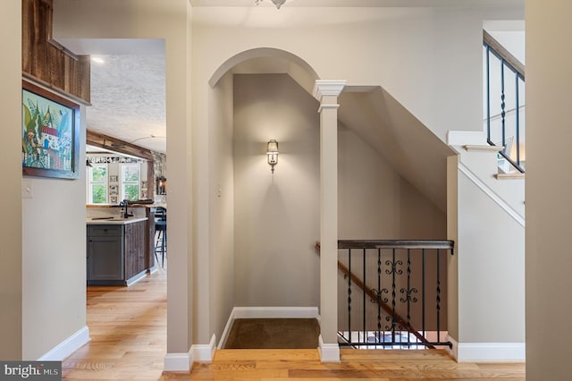 hallway with light hardwood / wood-style flooring and ornate columns