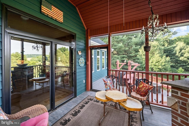 sunroom with lofted ceiling, a healthy amount of sunlight, and a notable chandelier