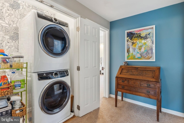 clothes washing area featuring laundry area, carpet floors, baseboards, and stacked washing maching and dryer