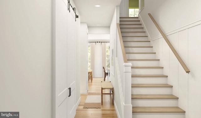 stairs with a barn door and hardwood / wood-style flooring