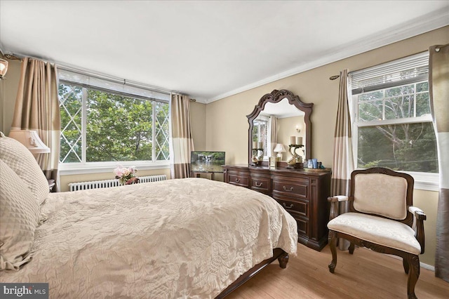 bedroom with light hardwood / wood-style floors, radiator heating unit, and ornamental molding