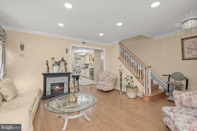 living room featuring ornamental molding, wood-type flooring, and a stone fireplace