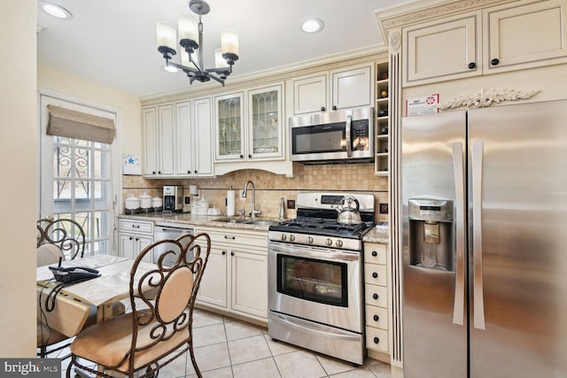 kitchen featuring sink, hanging light fixtures, appliances with stainless steel finishes, cream cabinetry, and light stone counters