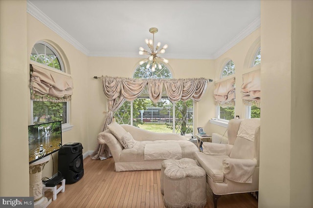 sitting room featuring plenty of natural light, hardwood / wood-style flooring, ornamental molding, and a notable chandelier