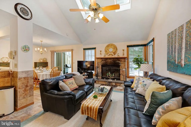 living room featuring ceiling fan with notable chandelier, a stone fireplace, and high vaulted ceiling