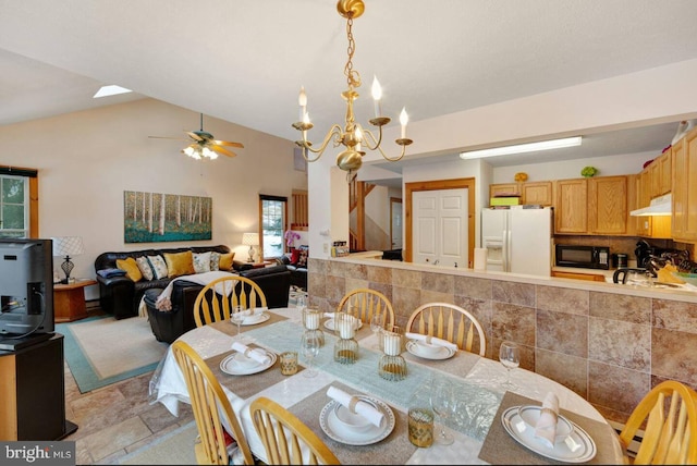 dining space with ceiling fan with notable chandelier and vaulted ceiling