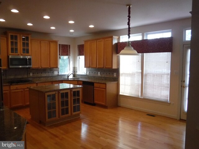 kitchen featuring sink, a center island, plenty of natural light, decorative light fixtures, and appliances with stainless steel finishes