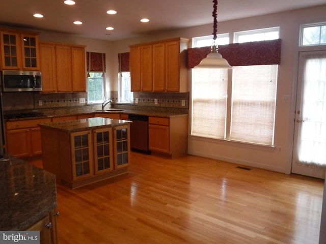 kitchen with stainless steel appliances, sink, light hardwood / wood-style floors, a kitchen island, and hanging light fixtures