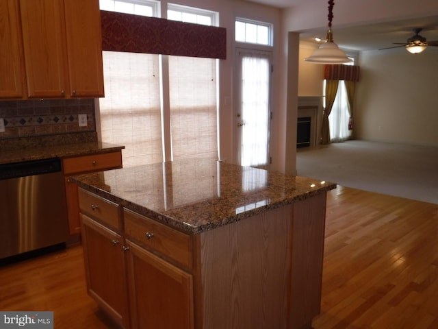 kitchen with tasteful backsplash, pendant lighting, light hardwood / wood-style flooring, dark stone countertops, and dishwasher