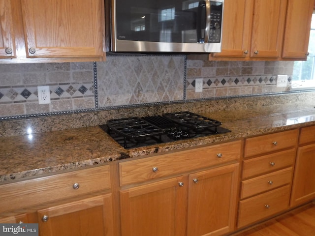 kitchen with black gas stovetop, light stone countertops, and tasteful backsplash