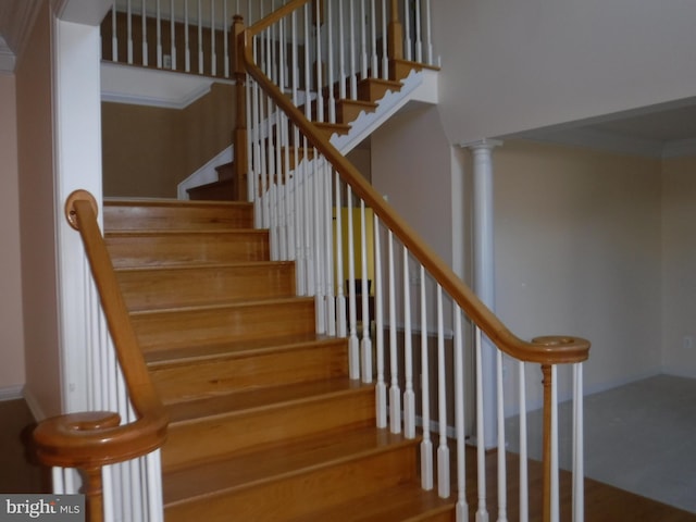 staircase with wood-type flooring and decorative columns