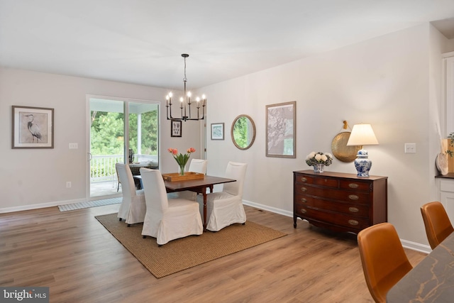 dining area with light wood-type flooring and a chandelier