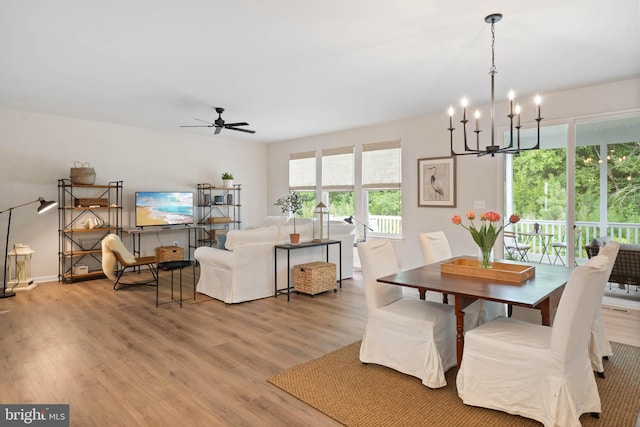 dining room with ceiling fan with notable chandelier and light hardwood / wood-style floors