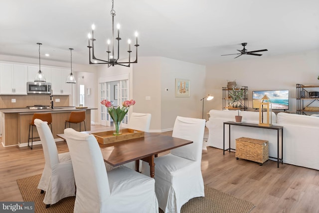 dining room with ceiling fan with notable chandelier and light wood-type flooring