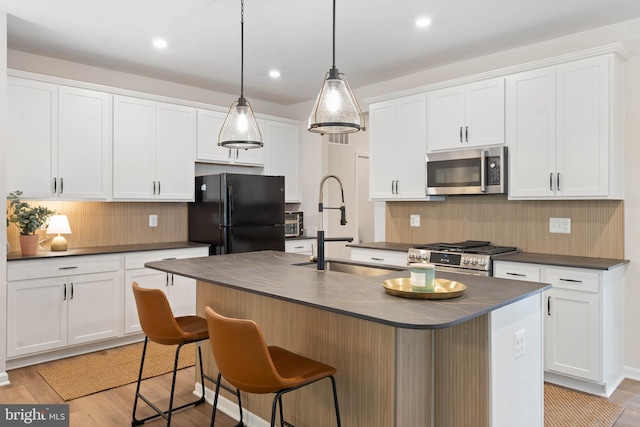 kitchen with white cabinetry, light wood-type flooring, stainless steel appliances, and a center island with sink