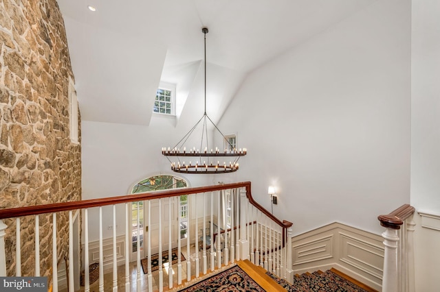 stairway featuring vaulted ceiling, a chandelier, and a healthy amount of sunlight