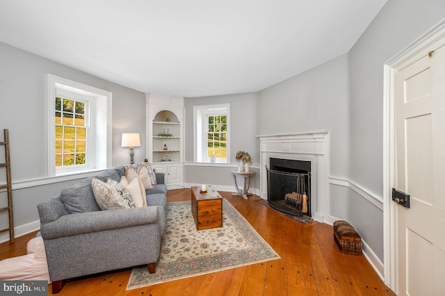 living room with built in features, a wealth of natural light, and hardwood / wood-style flooring