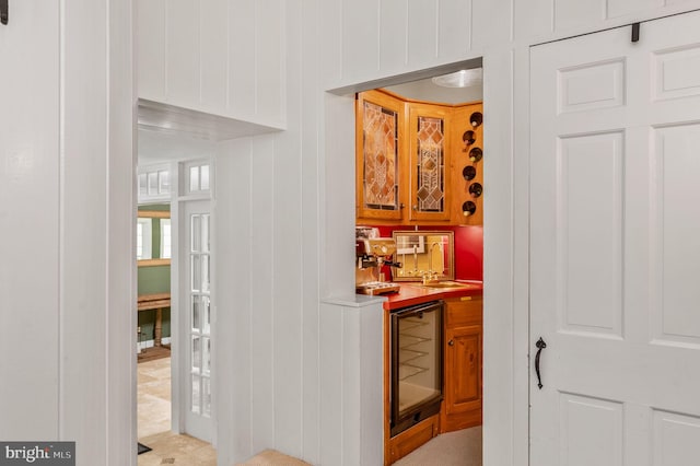 bar with beverage cooler, wooden walls, and sink