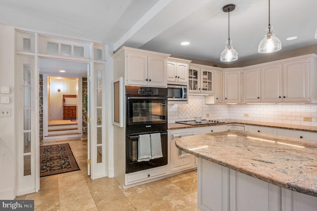 kitchen featuring stainless steel microwave, decorative light fixtures, tasteful backsplash, light stone countertops, and double oven