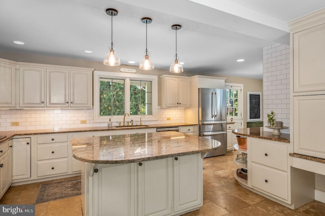 kitchen with a kitchen island, stainless steel appliances, dark stone counters, sink, and backsplash